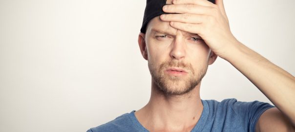 man in blue crew neck shirt covering his face