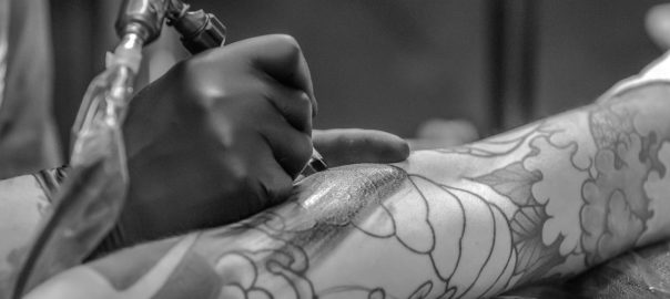 Grayscale Photo of Person Applying Tattoo