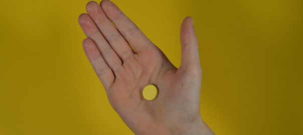 a person holding their hand out with a pill in it