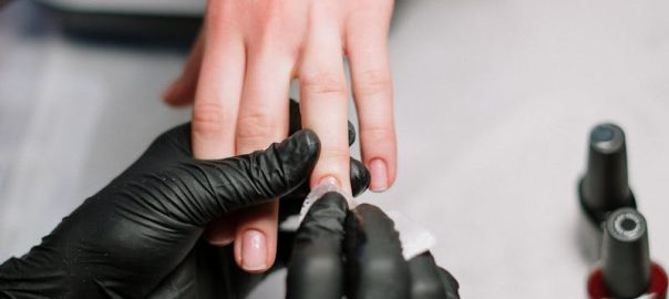 Close-up of a professional manicure with gel polish and black gloves in a salon.