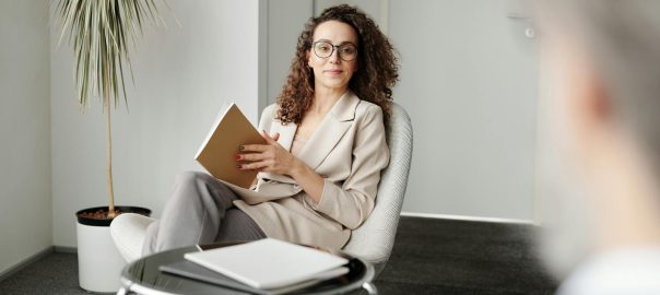 Businesswoman sitting in a modern office with a notebook, exuding professionalism and confidence.