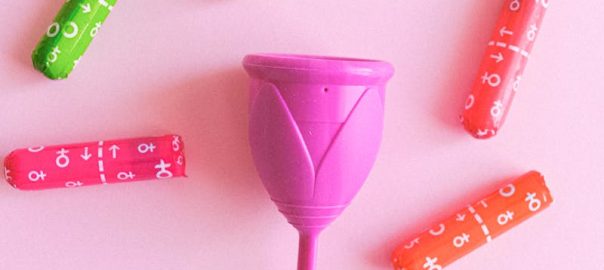 Vibrant menstrual cup and tampons on a pink backdrop, showcasing eco-friendly feminine hygiene options.