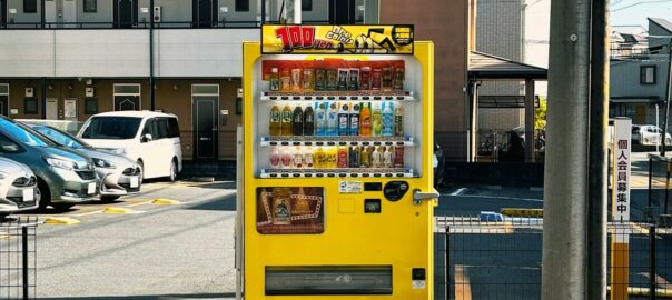 a yellow vending machine sitting on the side of a road